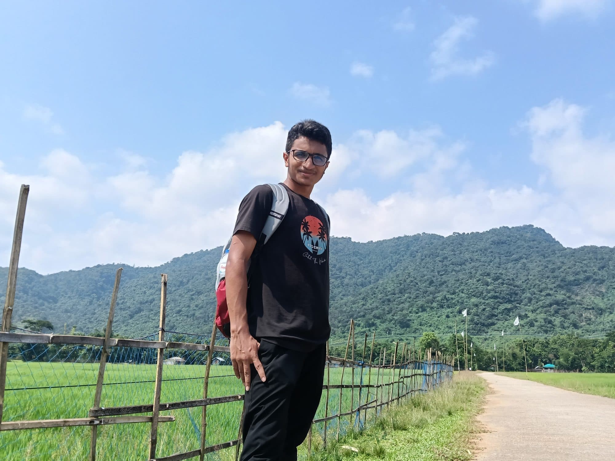 Mohammad Nasir on a fenced path below green hills in Sylhet