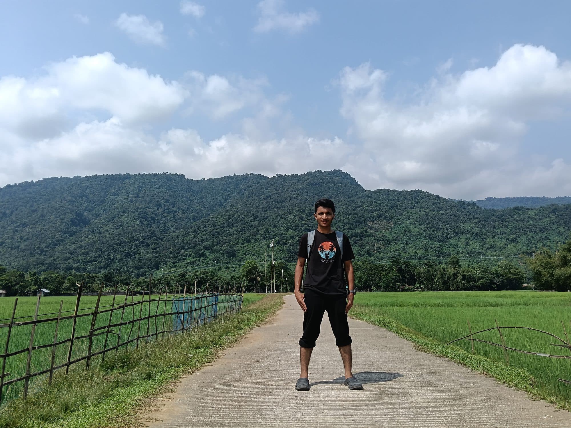 Mohammad Nasir standing on a village road between fields in Sylhet